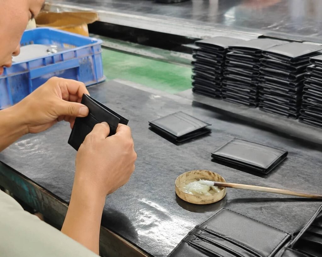 Leather wallet manufacturing — bifold wallets being assembled on a factory production line